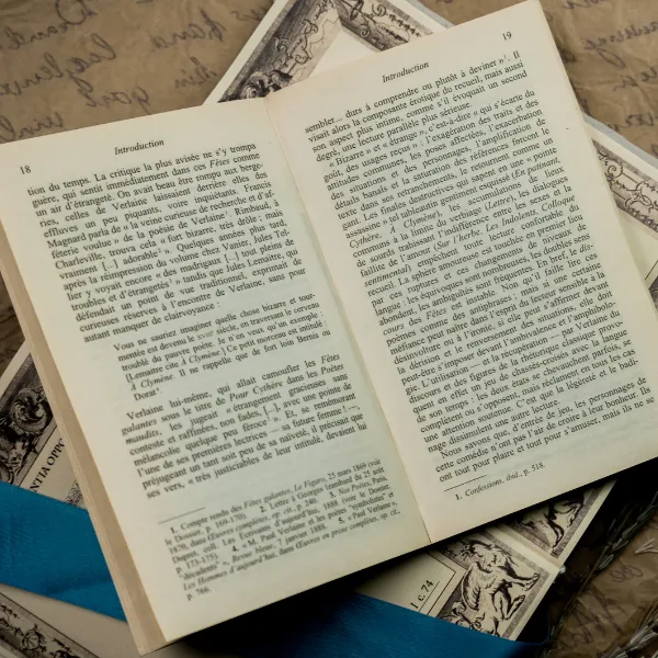 Close-up of old book written in French, silk blue ribbon and lavender on a background paper