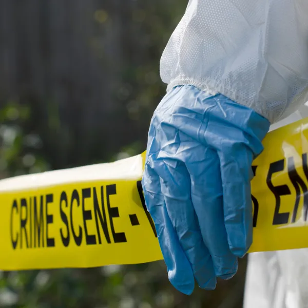 Forensic investigator working at a crime scene, holding police tap.