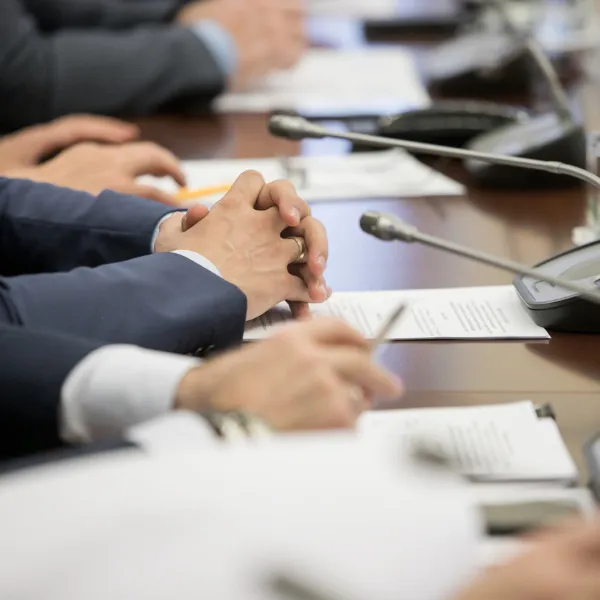 One of politician sitting by table with their hands over document during political conference.