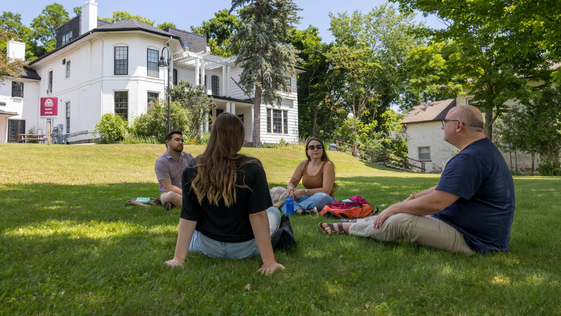 Four Trent students sitting outside near Traill College