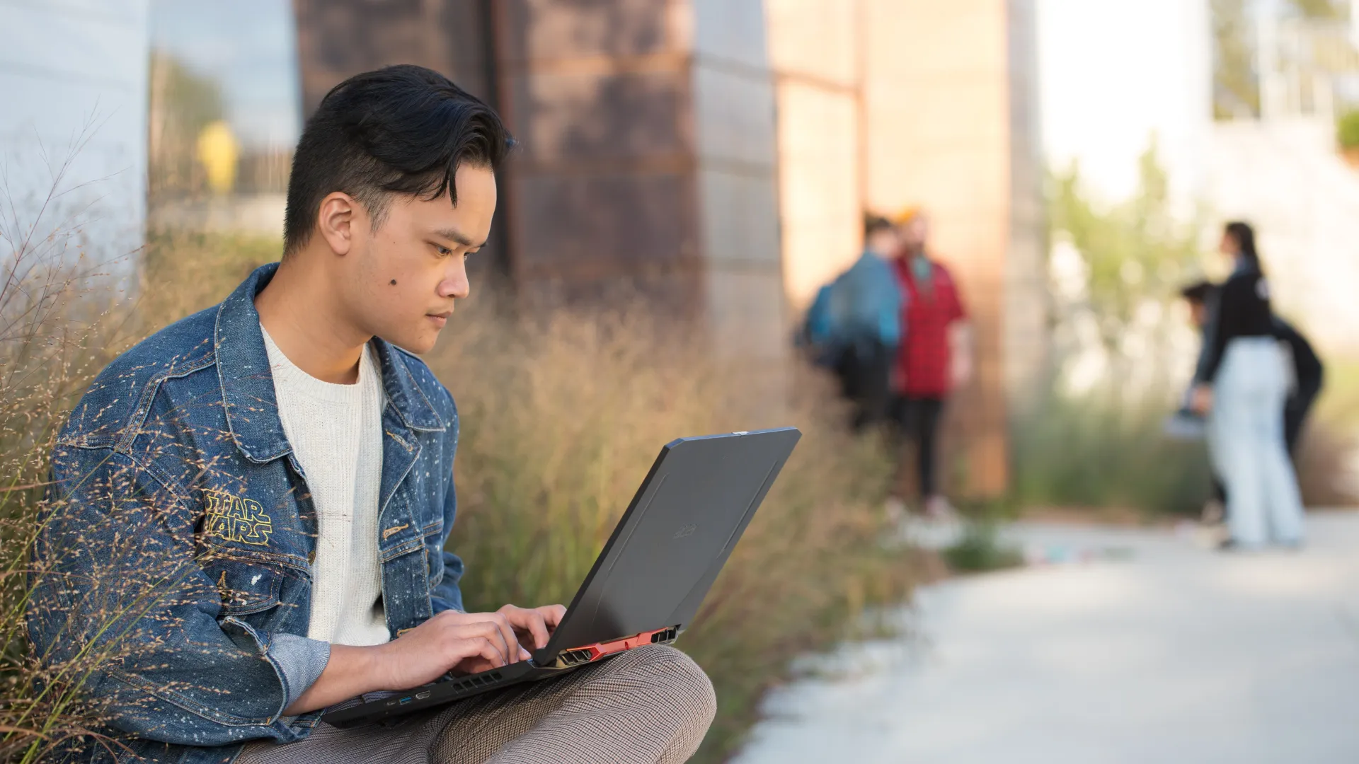 A student outside working on their computer