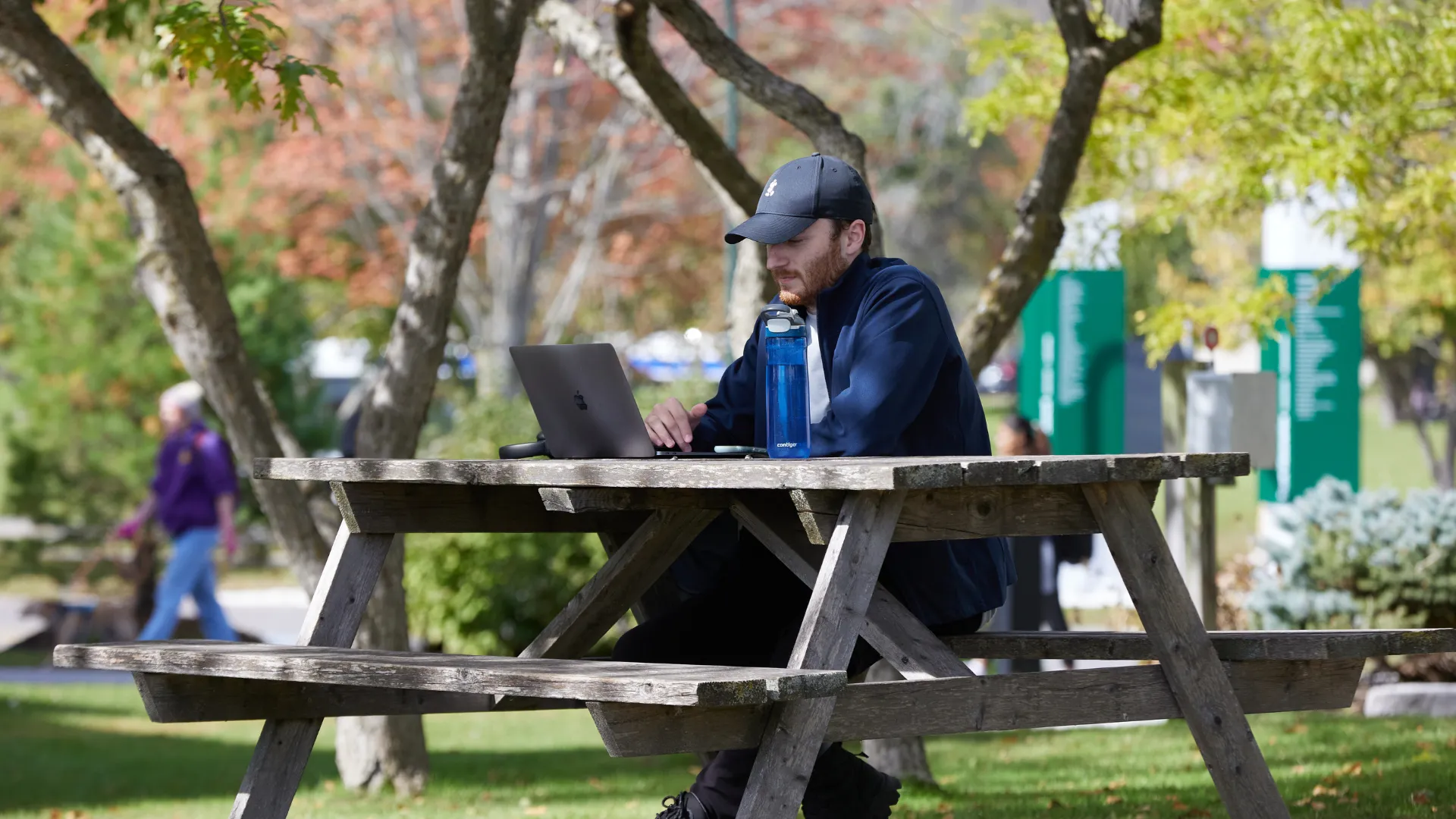 A Trent student outside working on their laptop
