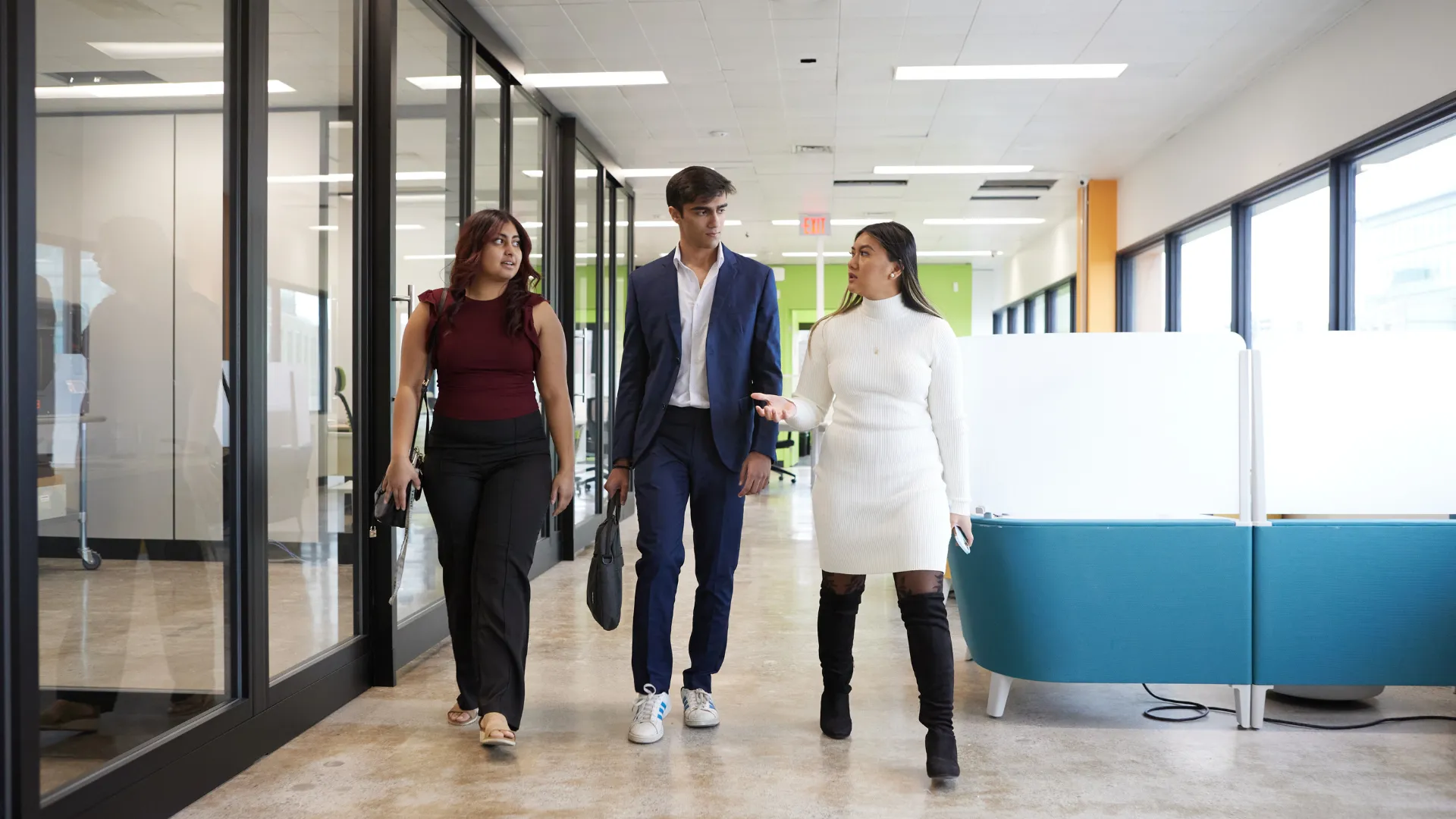 Three Trent students walking through the halls discussing class materials