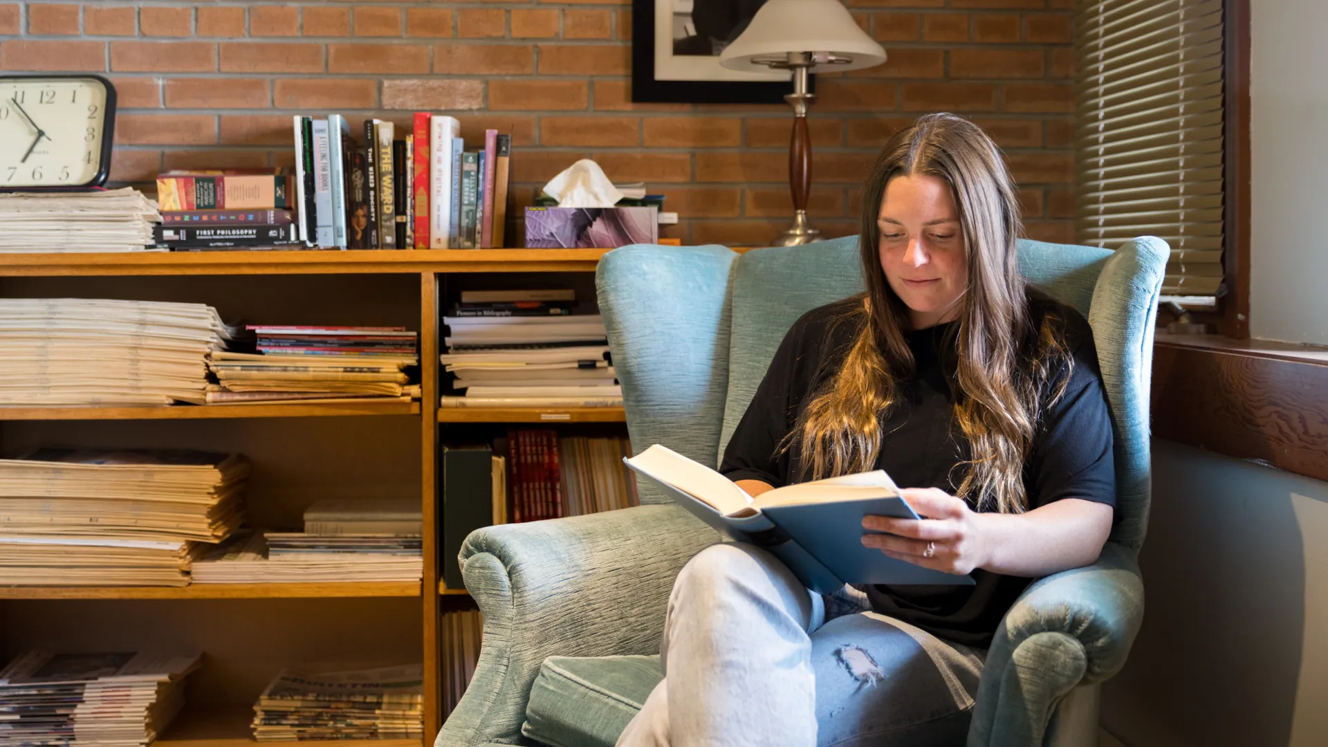 A Trent student sitting in a chair reading