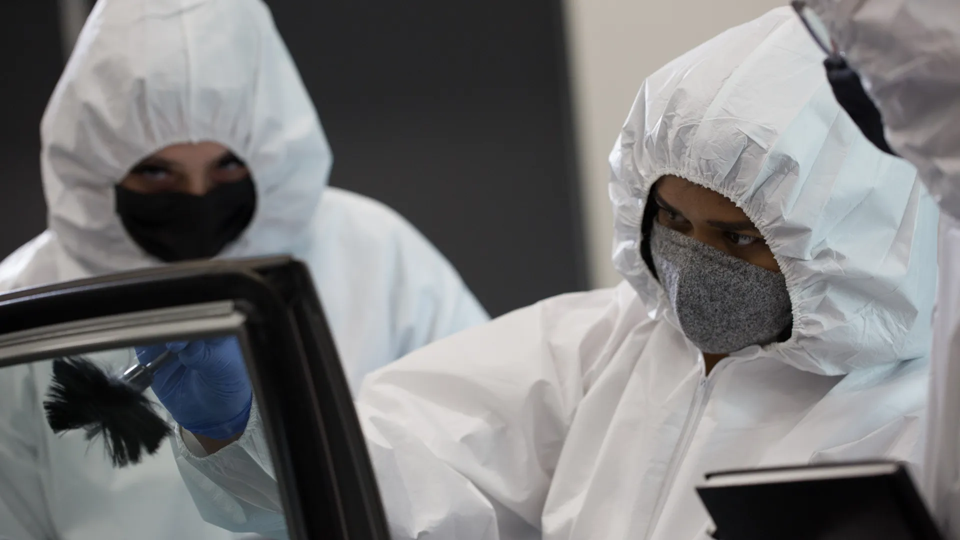 Forensic students dust a car window for fingerprints