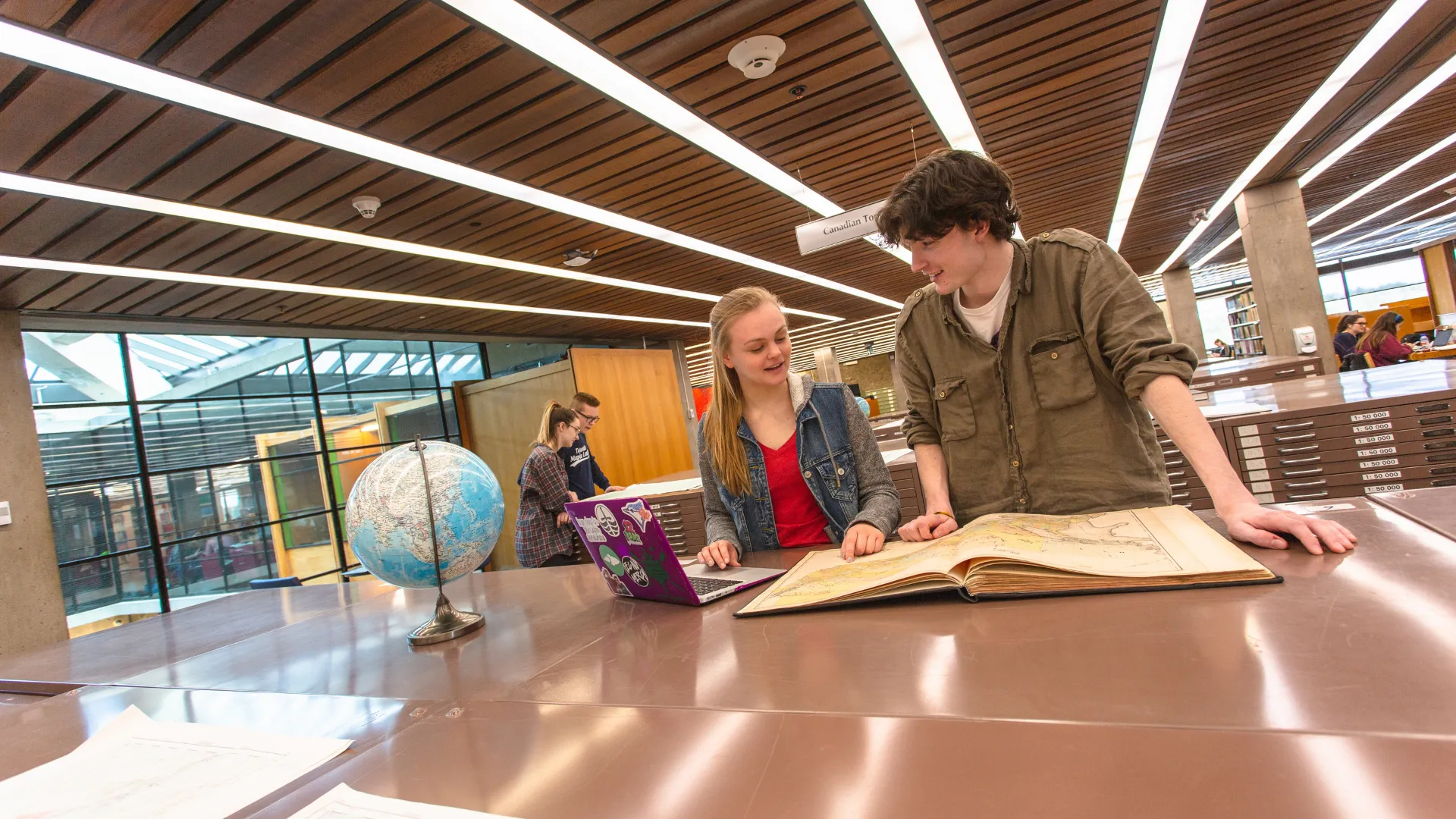 Trent students reading a textbook in the Bata Library on the Peterborough campus