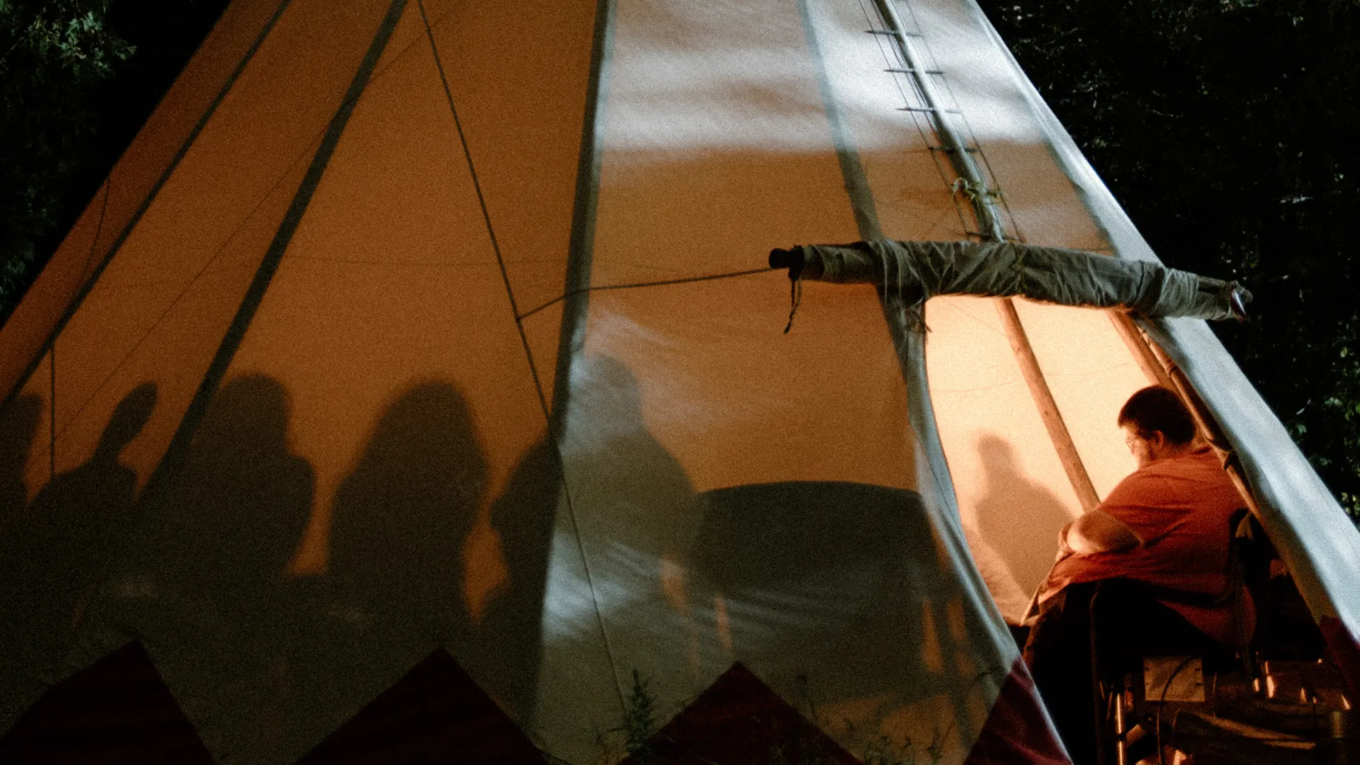Photo of people sitting inside of tipi as seen from the exterior