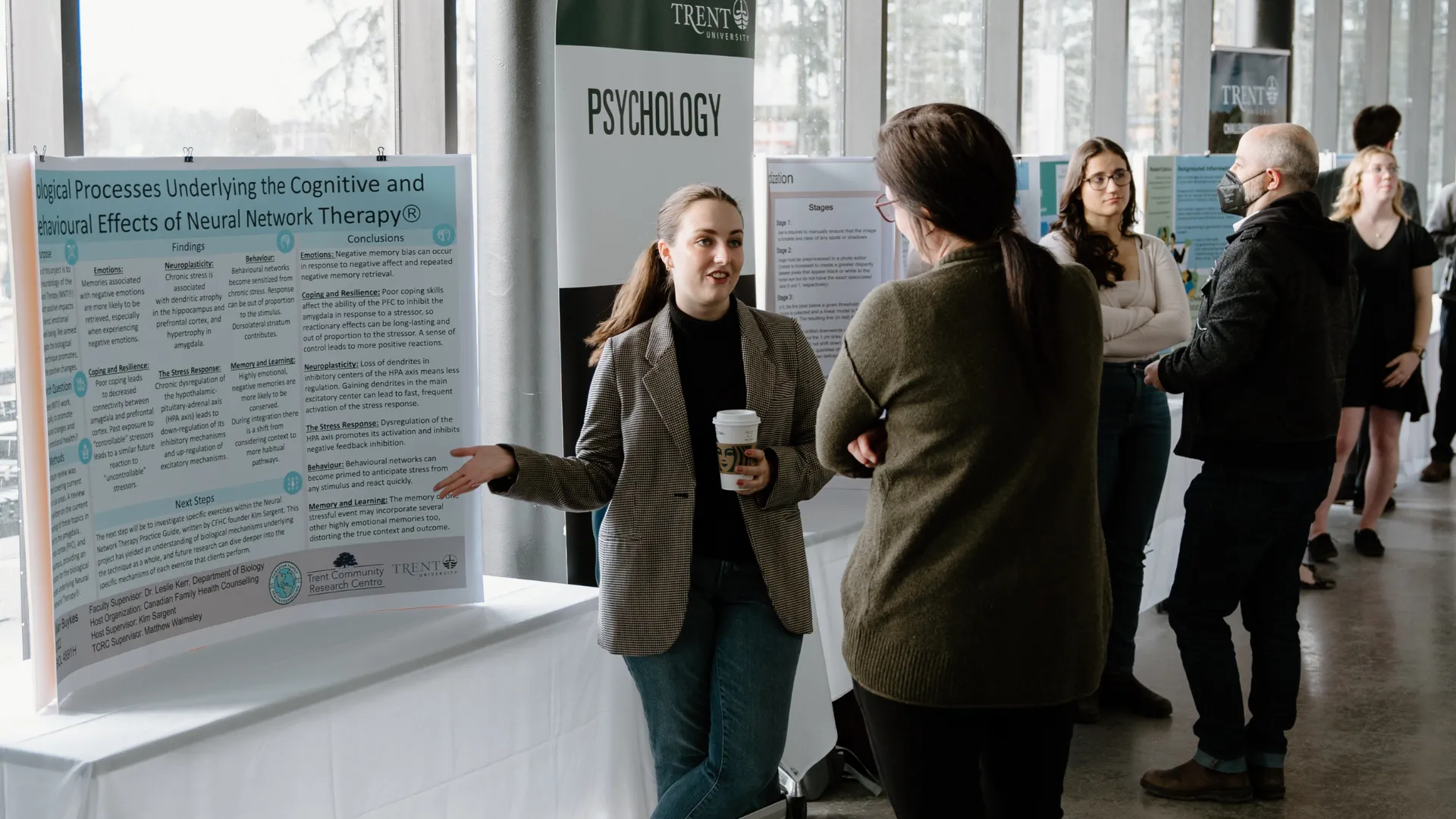 A student gives a poster presentation to an interested viewer