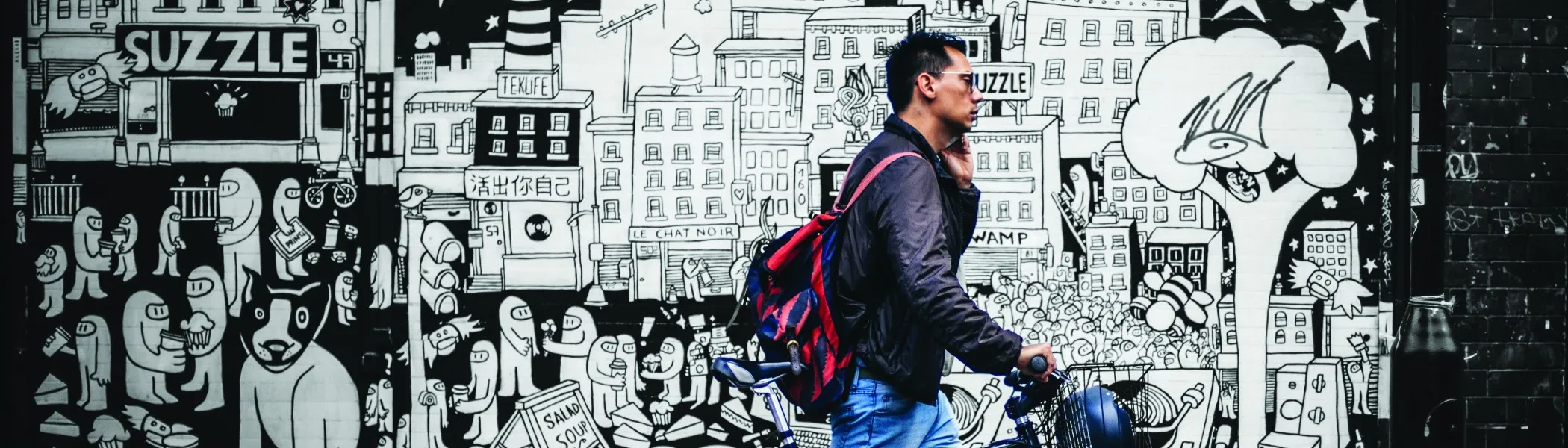 A man walking his bike past a mural