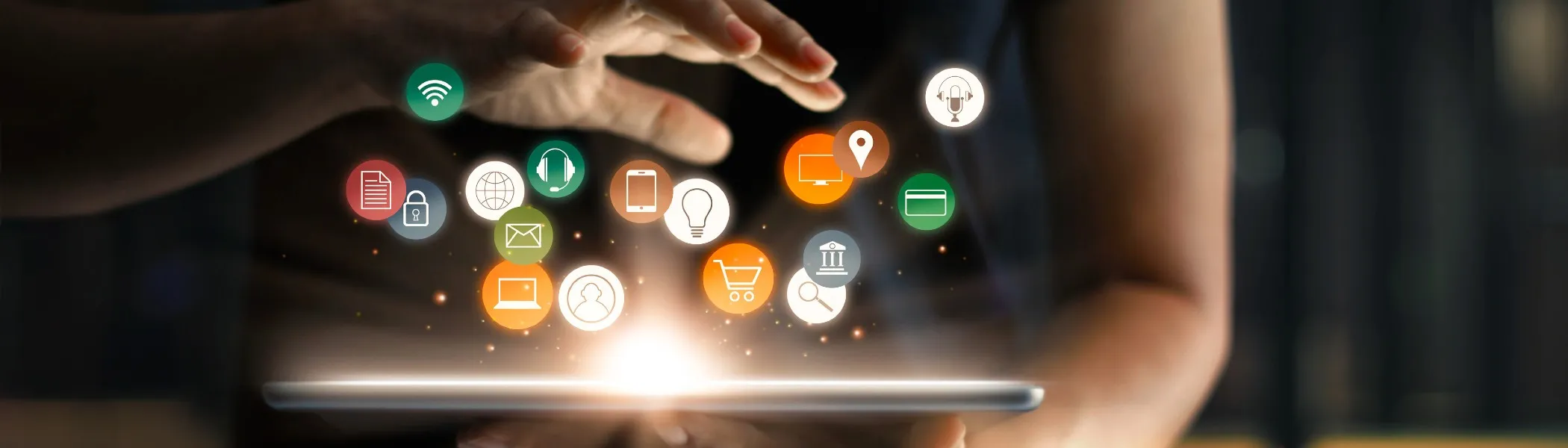 A person waving their hand over a tablet with floating icons