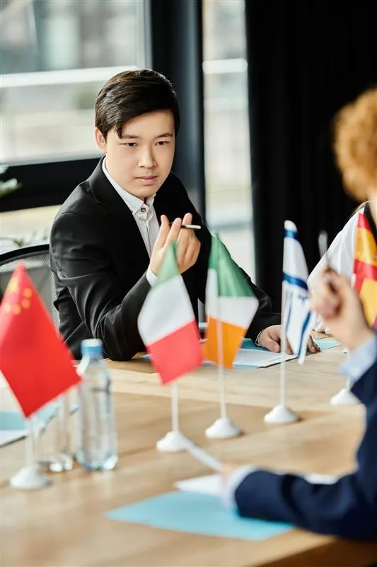 Photo of man in suit at boardroom table with various world flags on the table