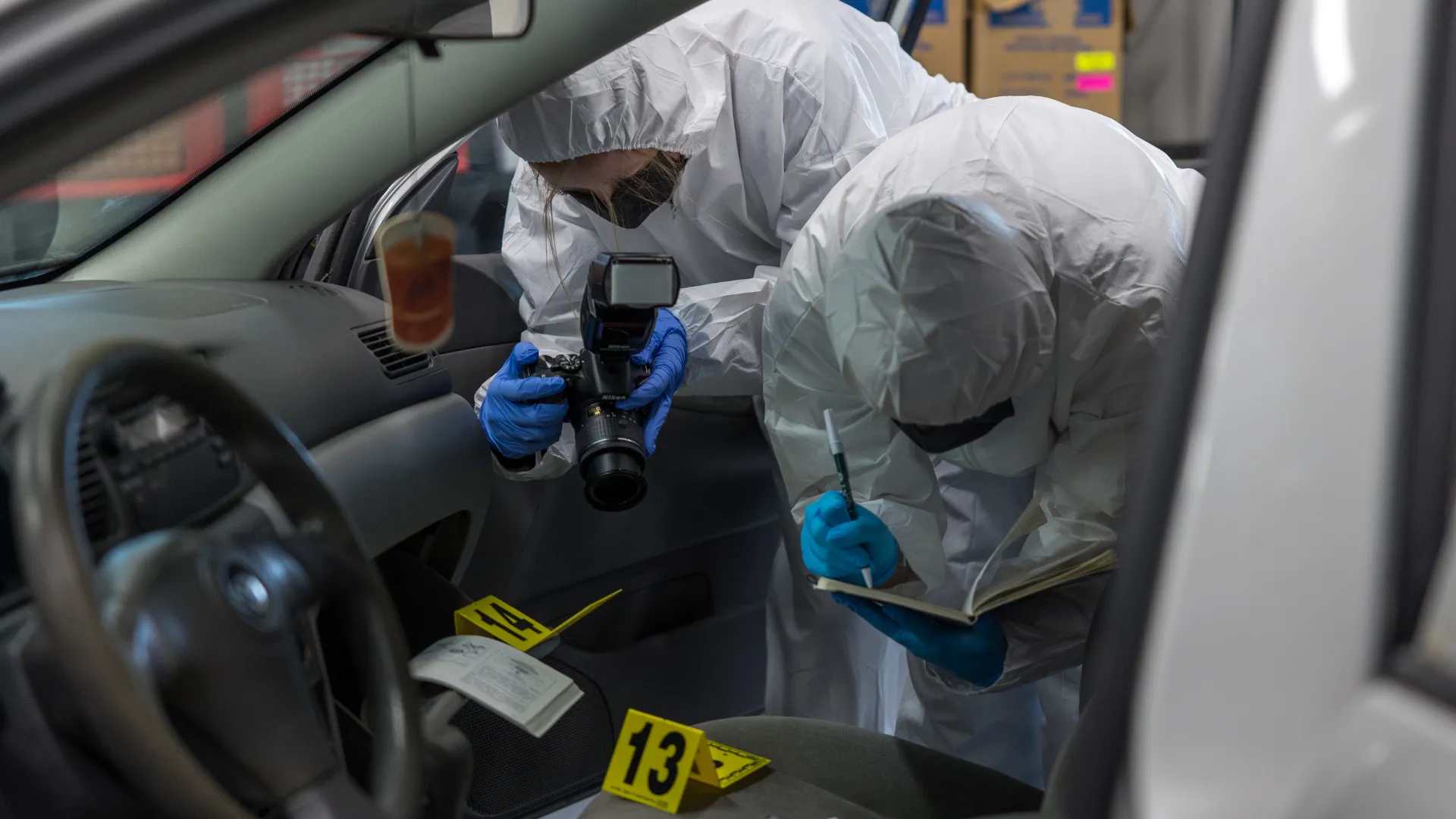 Forensics science crime scene, student taking photos of evidence in car.