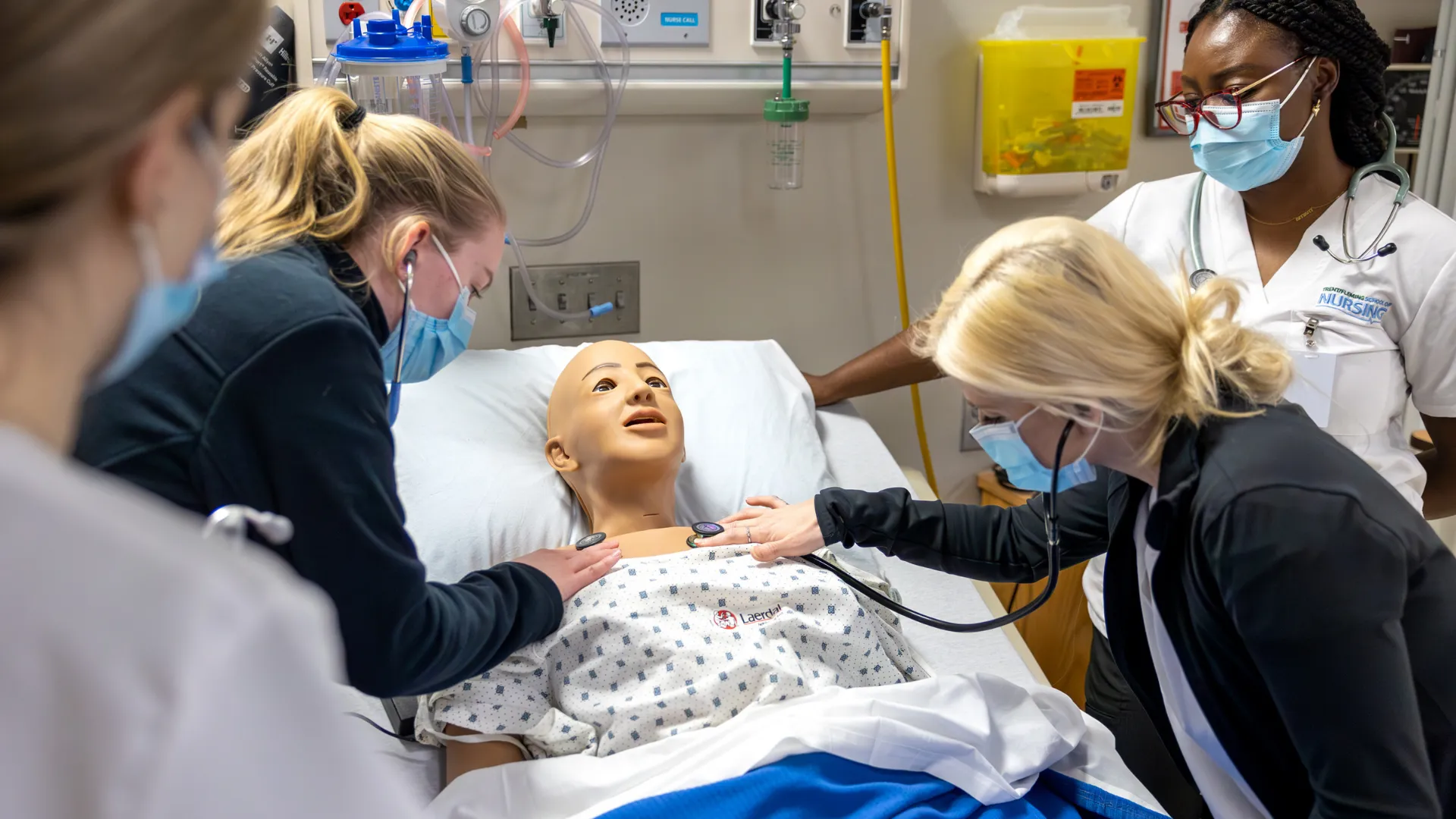 Trent nursing students in Trent Simulation Hub checking the breathing of the simulation mannequin.