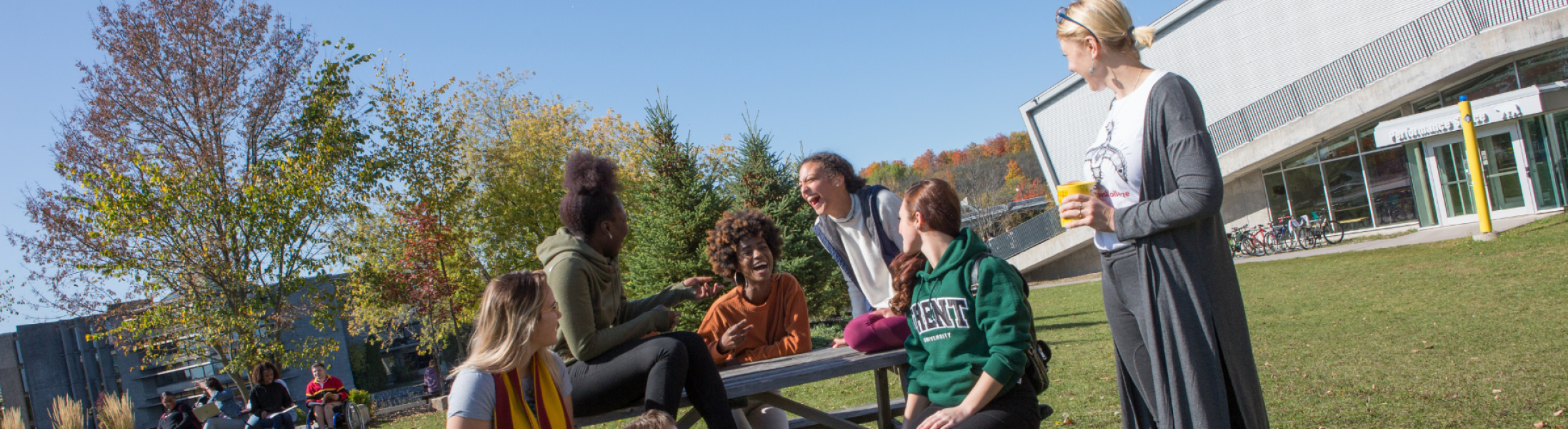 Group of students on picnic table laughing and chatting