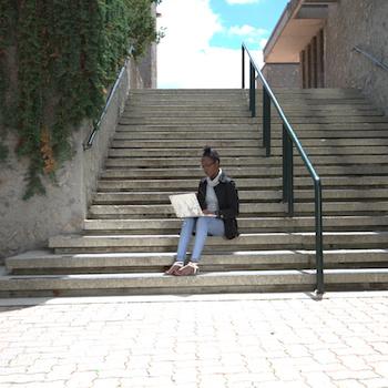 A student working on a laptop outside on stairs