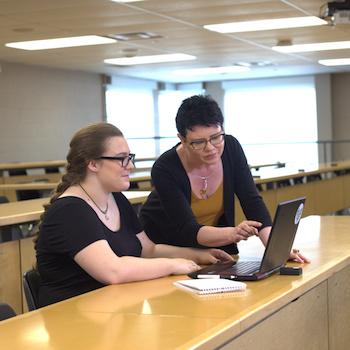 A professor helping a student at a desk