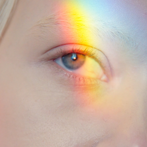 A child's eye with a rainbow light shining on it.