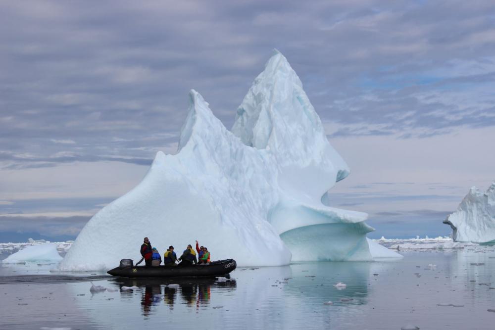 People in a boat in front of iceberg