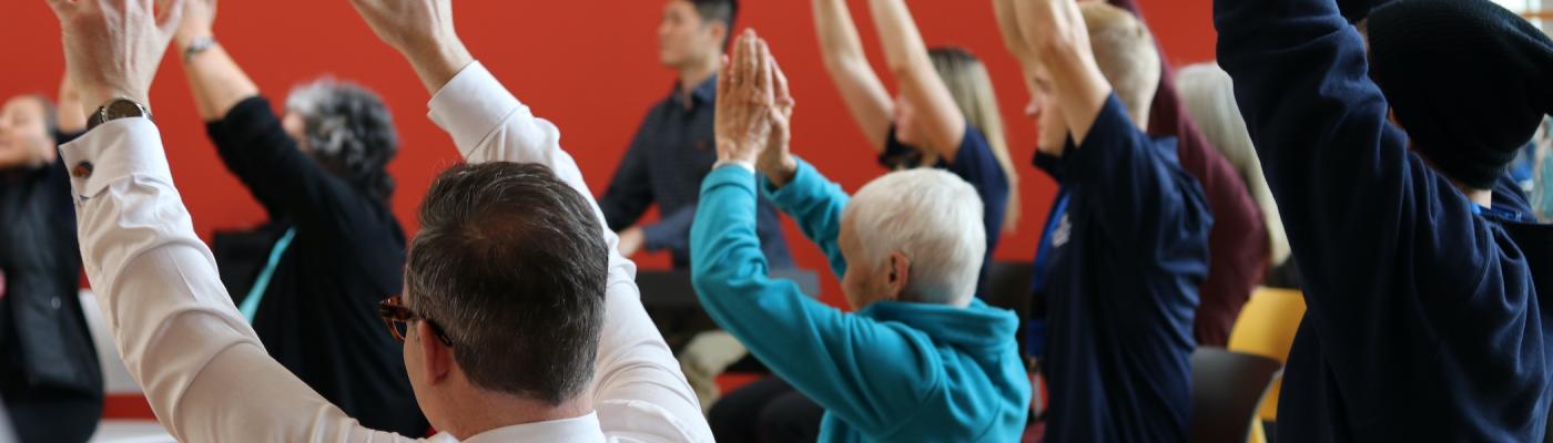 A group of seniors raising their hands during a fitness activity.