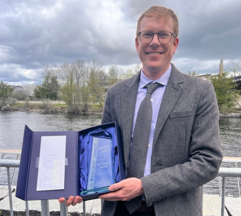 Thomas Hossie holding the Research Impact Award