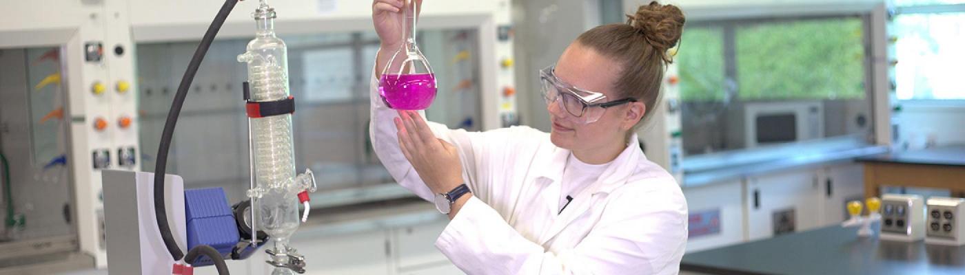 Scientist inspecting a volumetric flask filled with pink liquid