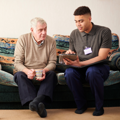 Younger man of colour speaking to older gentleman on couch