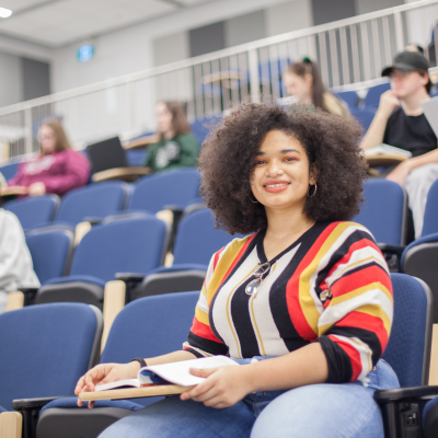 Female student smiling at camera from lecture hall seat