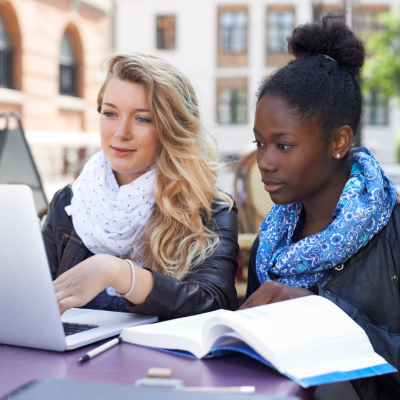 Photo of two girls, one white, one black, working on a laptop together