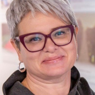 Photo of Marina Morgenshtern, female with grey hair and red glasses, smiling