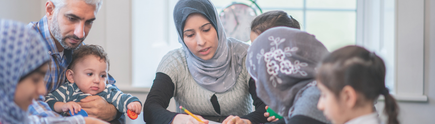 Photo of a group of immigrants working with someone around a table