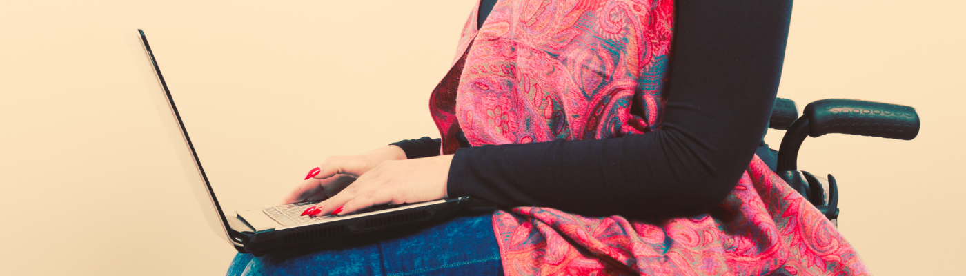 Cropped image of woman sitting in a wheelchair working on a laptop