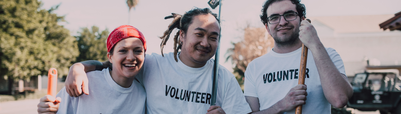 Group of three young people linking arms, wearing volunteer t-shirts