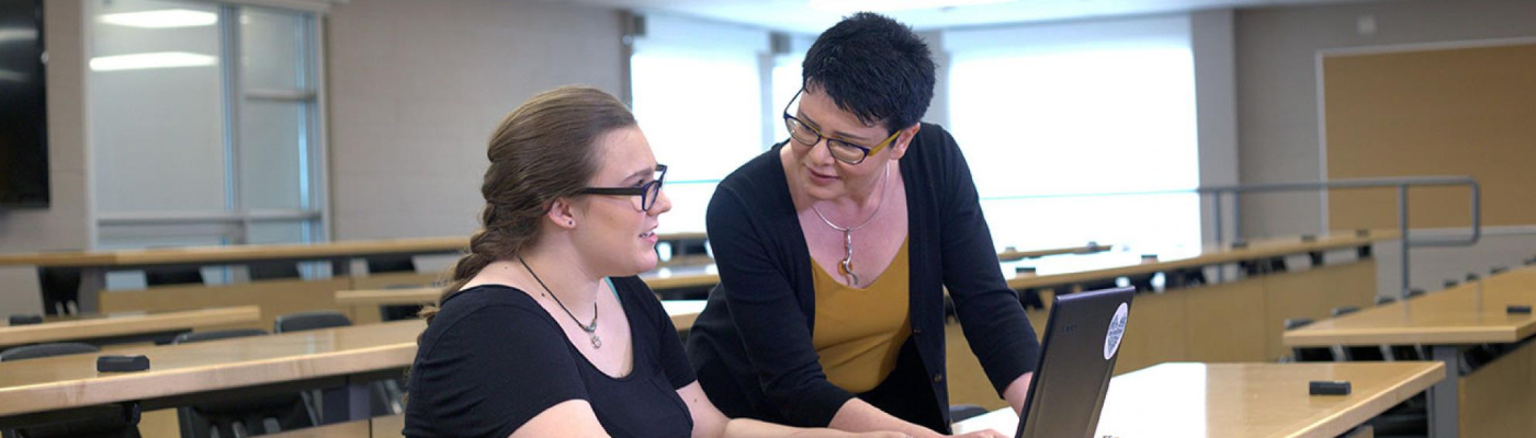 Faculty member leaning over and helping student answer question