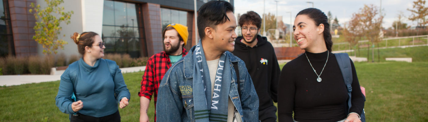 Group of 5 students walking and talking across Trent Durham campus