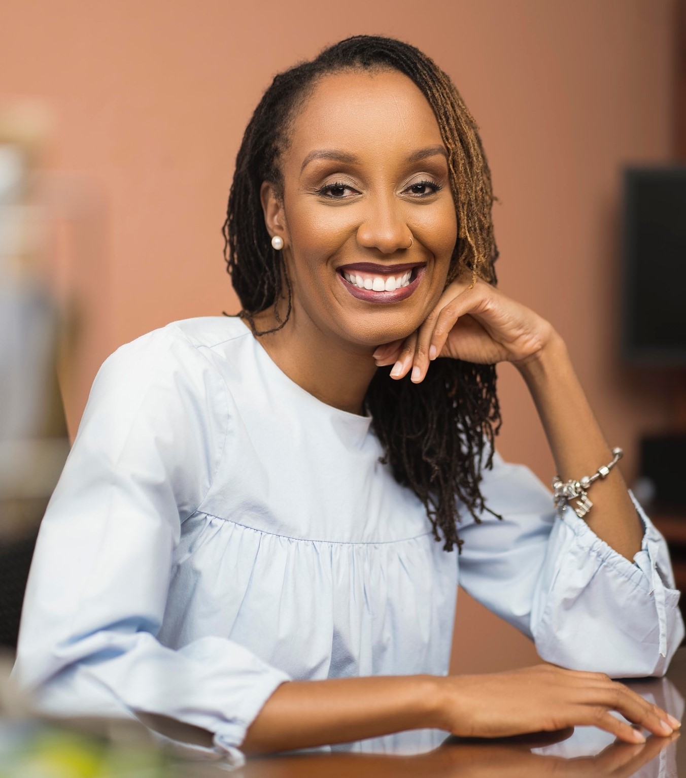 "smiling black woman in light blue shirt"