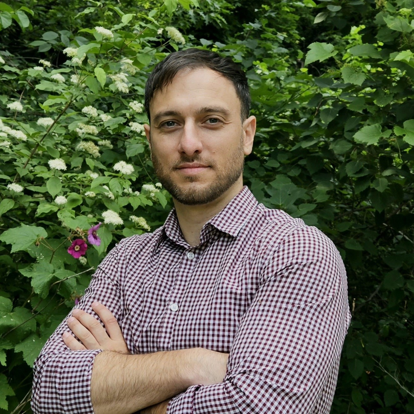 "white man in checkered shirt with tree background"
