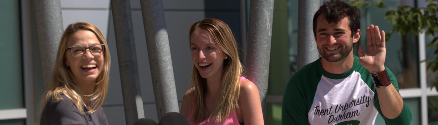 Three students waving and laughing
