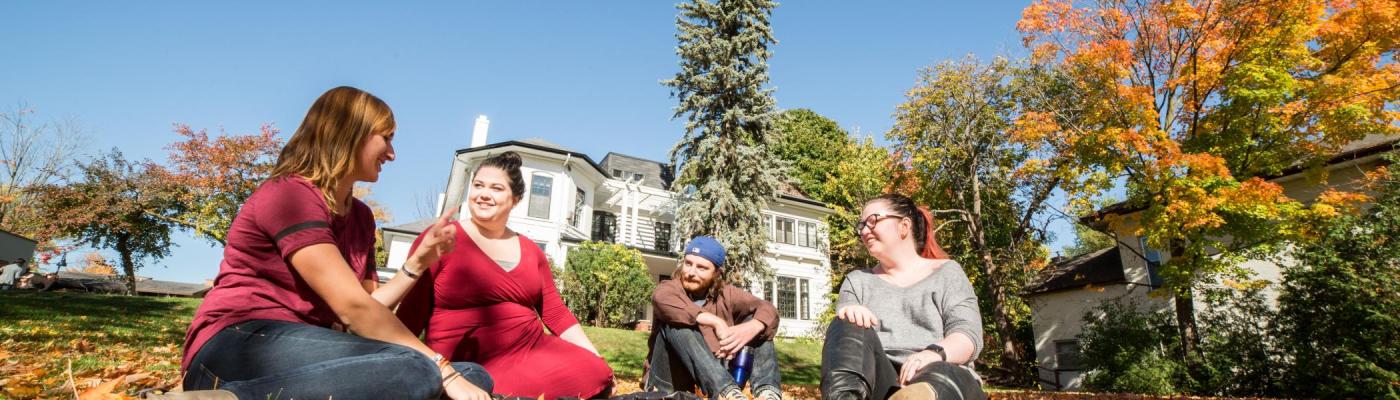 Group of students sitting outside talking and laughing 
