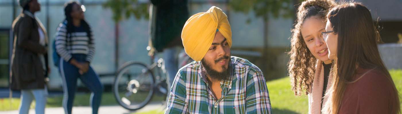 Trent students sitting outside on a bench chatting
