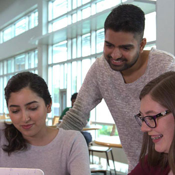 Three students looking at a laptop