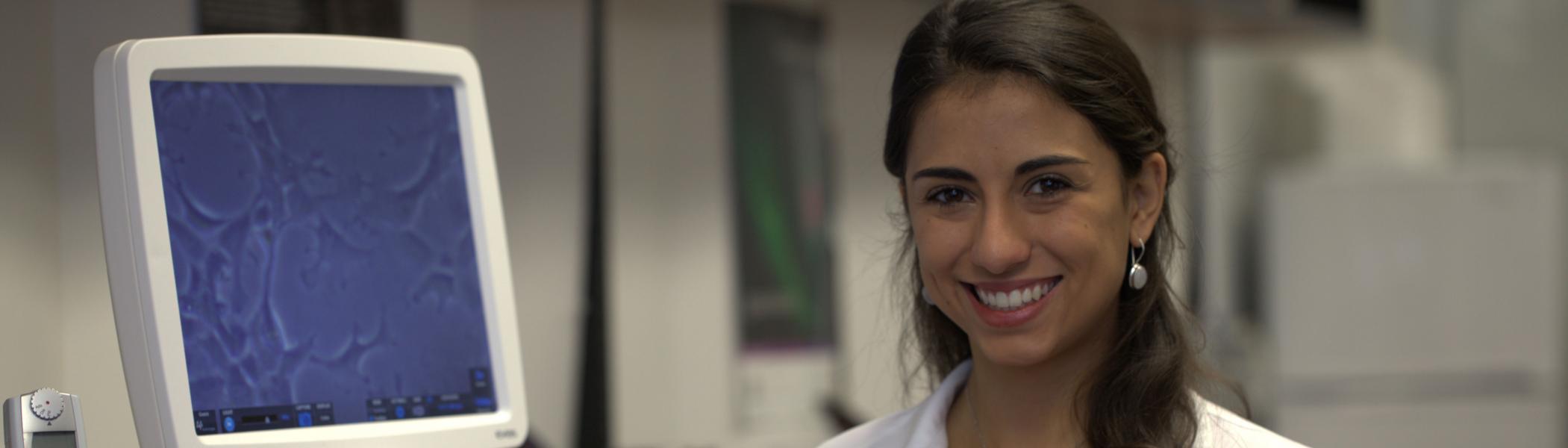 Student in lab smiling into camera
