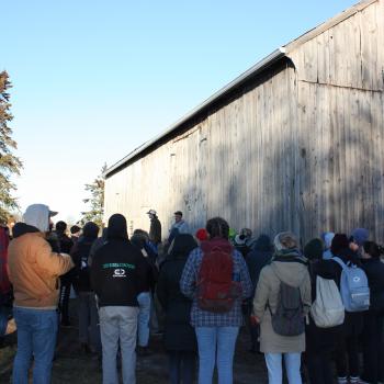 group of people standing outside a barn