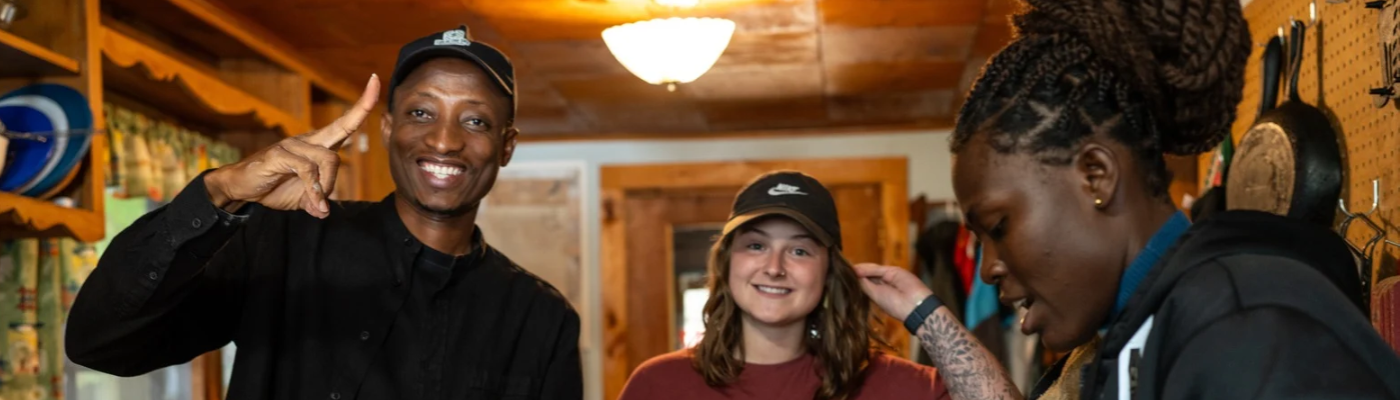Sustainability Studies MA students smiling at camera while making a meal together at the Program Retreat