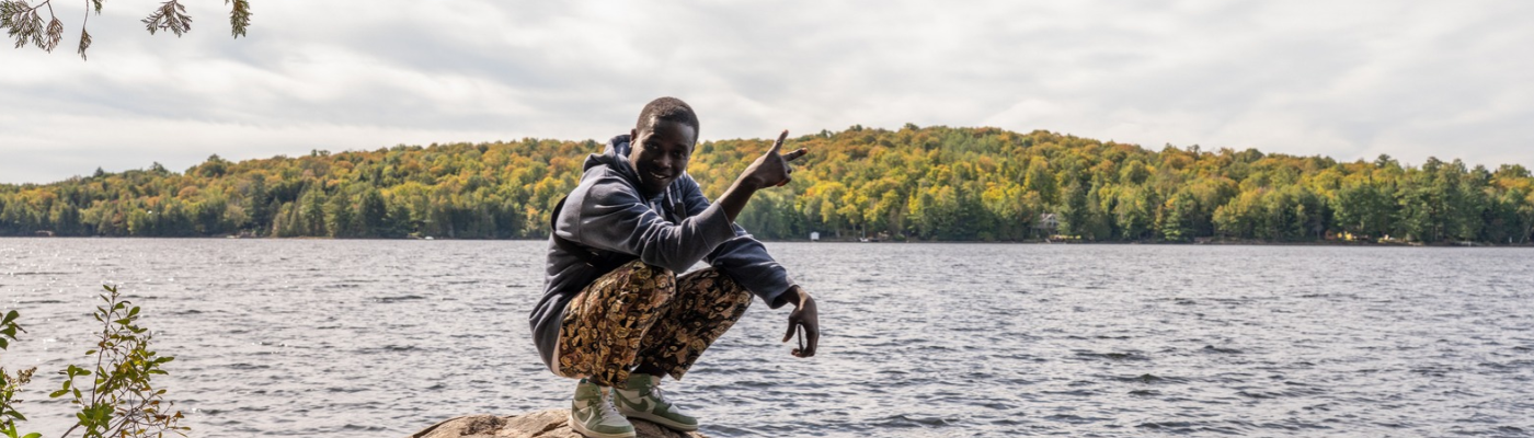 student from Sustainability Studies Program smiling in front of Lake while attending Program Retreat at Windy Pines