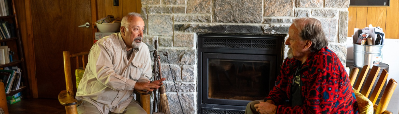 two faculty from Sustainability Studies sitting in front of fireplace talking