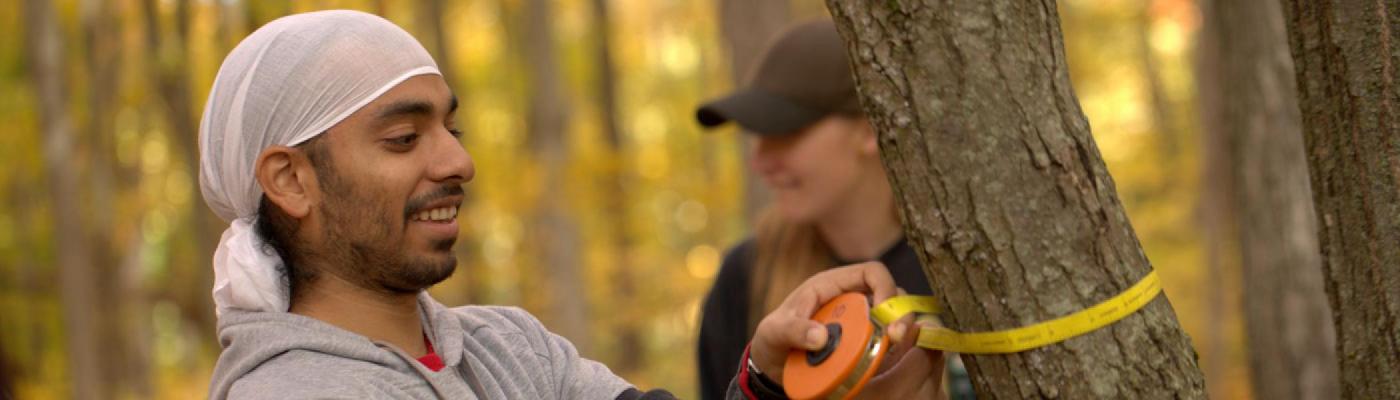 Sustainability M.A. student taking a measurement in the forest