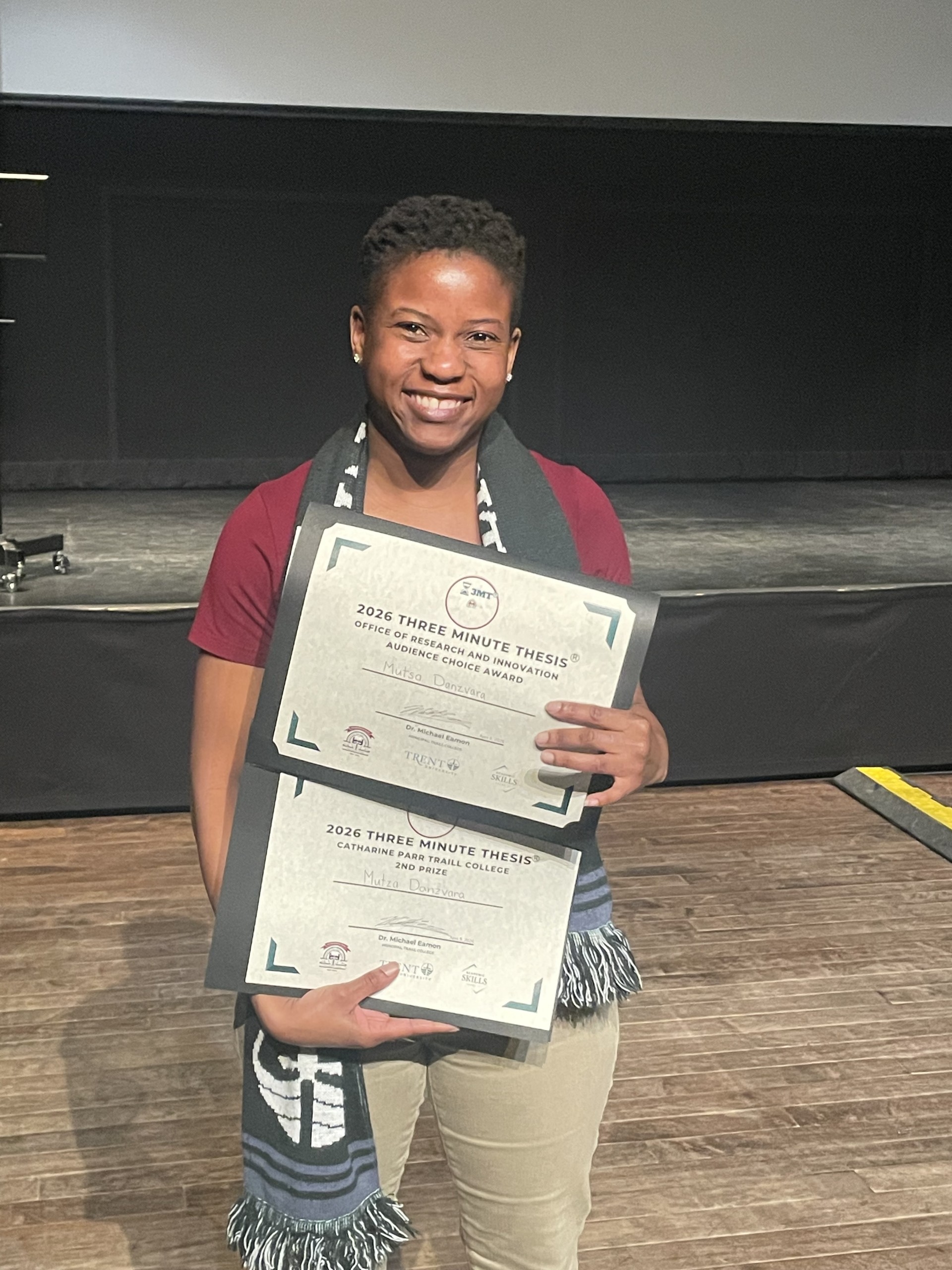 student, Mutsa Dazavara, smiling holding 2 award certificates in her hand