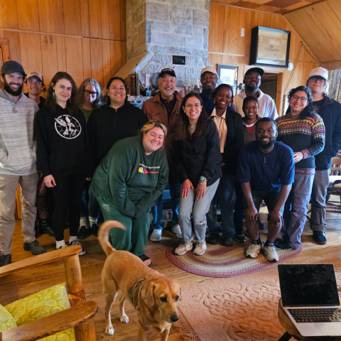 students standing in front of fireplace with dog