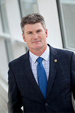 Man in suit and tie with shorter hair near the science building.