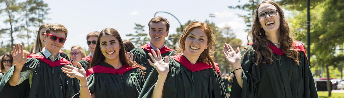 A group of students at their Trent University convocation wearing gowns and smiling.